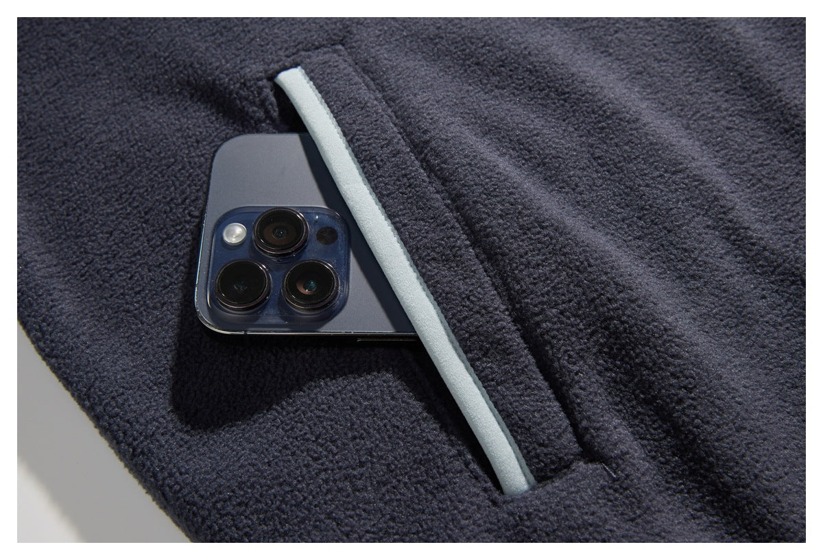 Close-up of a dark navy fleece jacket pocket with pale gray trim holding a smartphone.