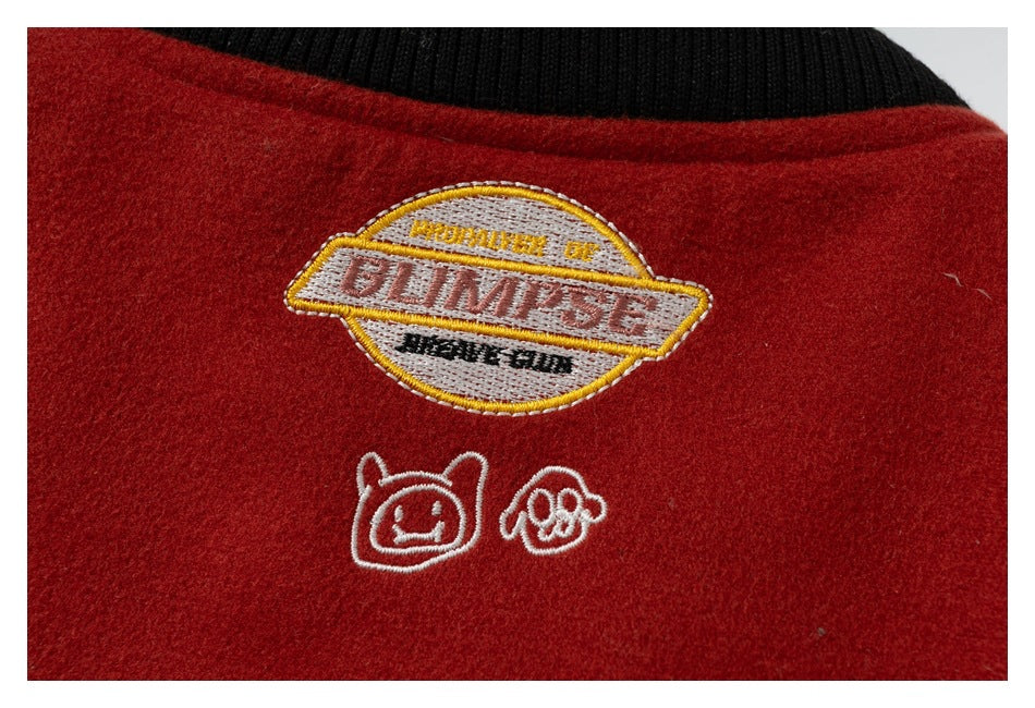 Close-up of a red garment with an embroidered patch, small doodles, and a black ribbed collar.