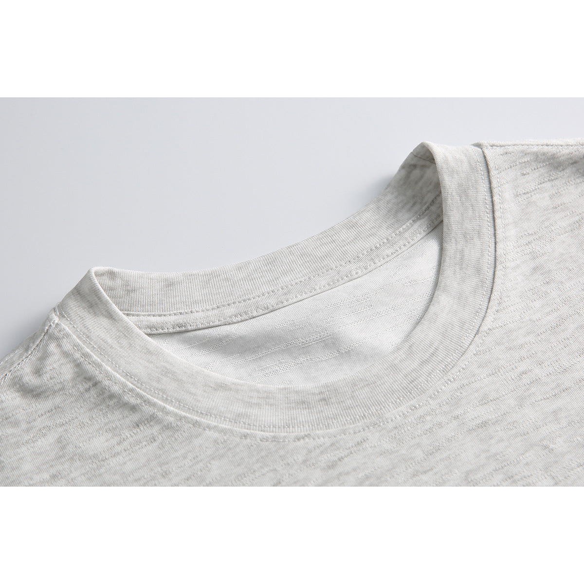 Close-up of a light gray heather T-shirt's ribbed crew neckline and shoulder seams.