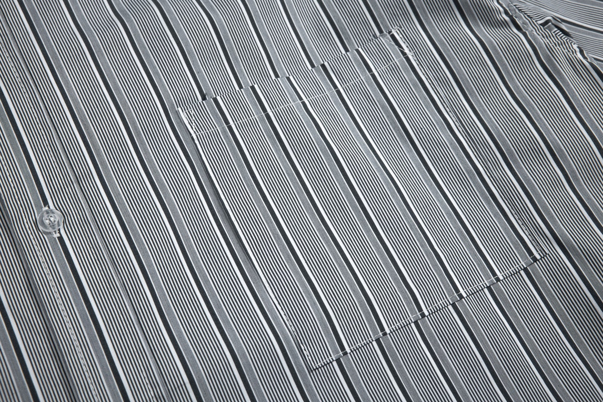 Close-up of a chest pocket on a black, gray, and white vertically striped shirt.