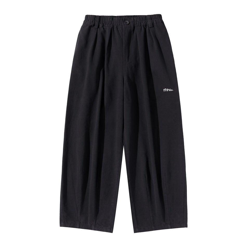 Black wide-leg pleated pants with elastic waistband, button front and small white logo, flat front view