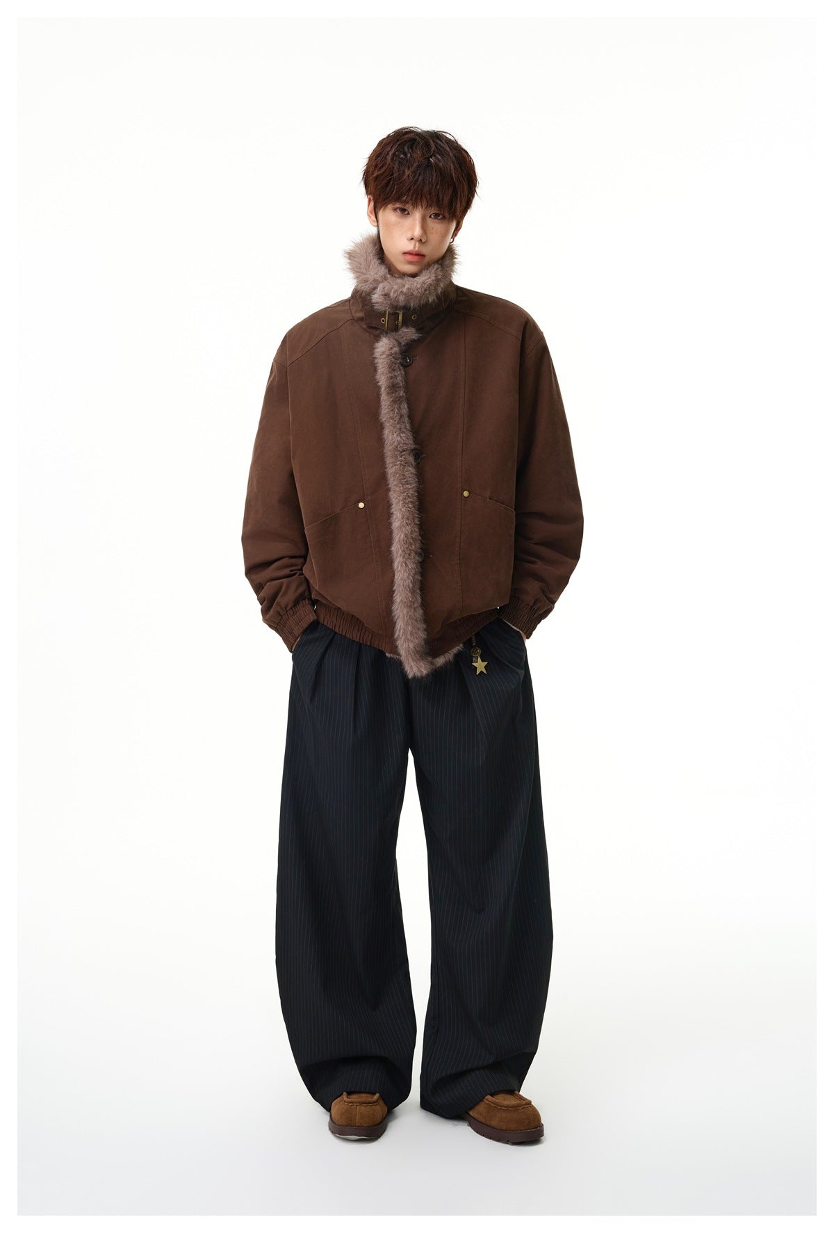 Model standing in the dark brown fleece-trimmed jacket with wide pinstripe pants and brown suede shoes, full-length view