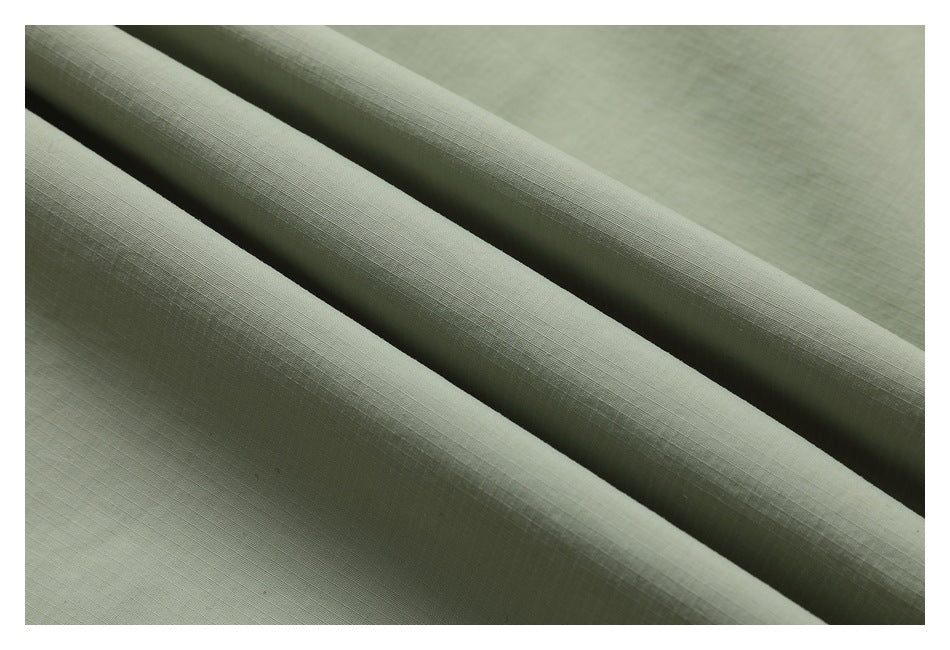 Macro view of sage-green garment fabric showing its fine grid-like weave.