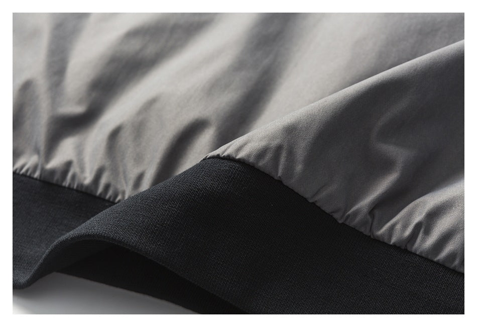 Close-up of a gray jacket hem finished with a wide black rib-knit band.
