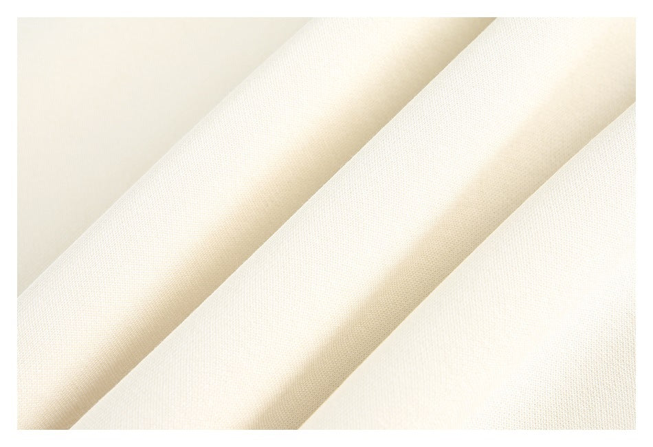 Close-up of cream fabric arranged in soft folds, showing its fine surface texture.