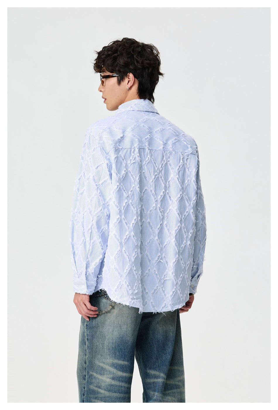 Model viewed from behind wearing a light blue pinstriped shirt with frayed diamond patterns across the back.