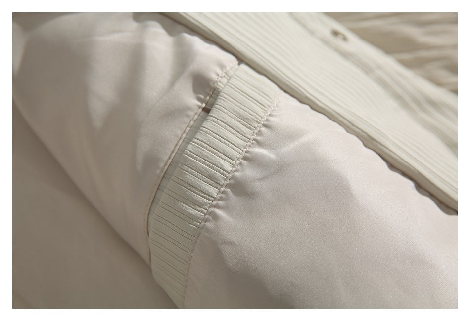 Close-up of the cream jacket’s sleeve seam and narrow ribbed cuff detail.
