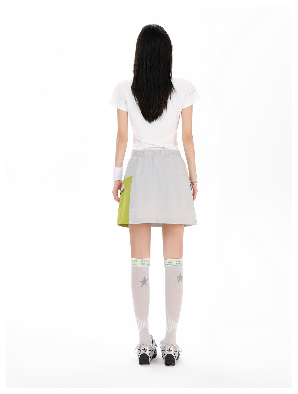 Back view of a model wearing a light gray mini skirt with a lime green side panel and an elastic waistband.