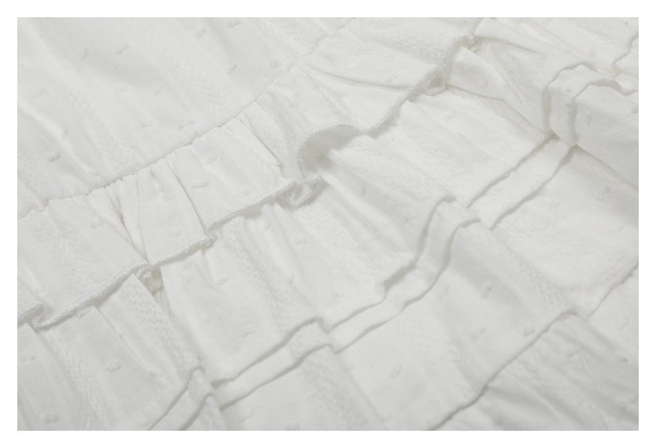 Close-up showing the textured fabric and layered ruffle seams of a white skirt.