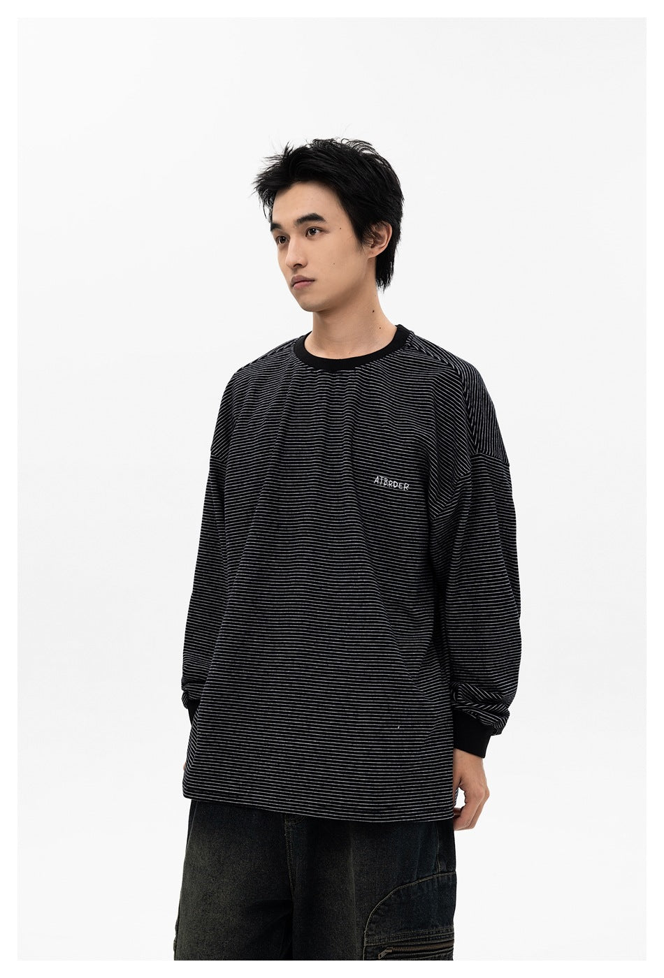 Model wearing black striped oversized long-sleeve crew-neck top with ribbed cuffs and dark cargo pants, front view