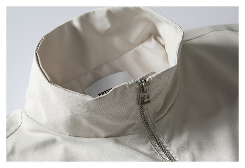 Close-up of an off-white jacket’s tall collar, lining, and front zipper.
