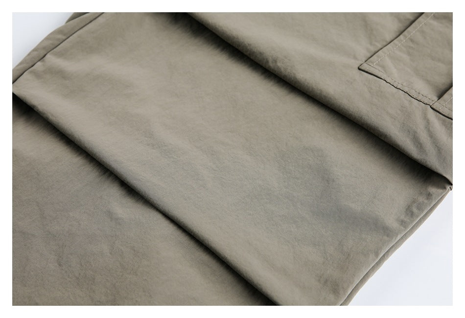 Close-up of the smooth olive-gray trouser fabric and folded leg.