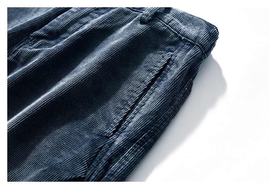 Close-up of a side pocket and ribbed fabric on dark blue corduroy trousers.