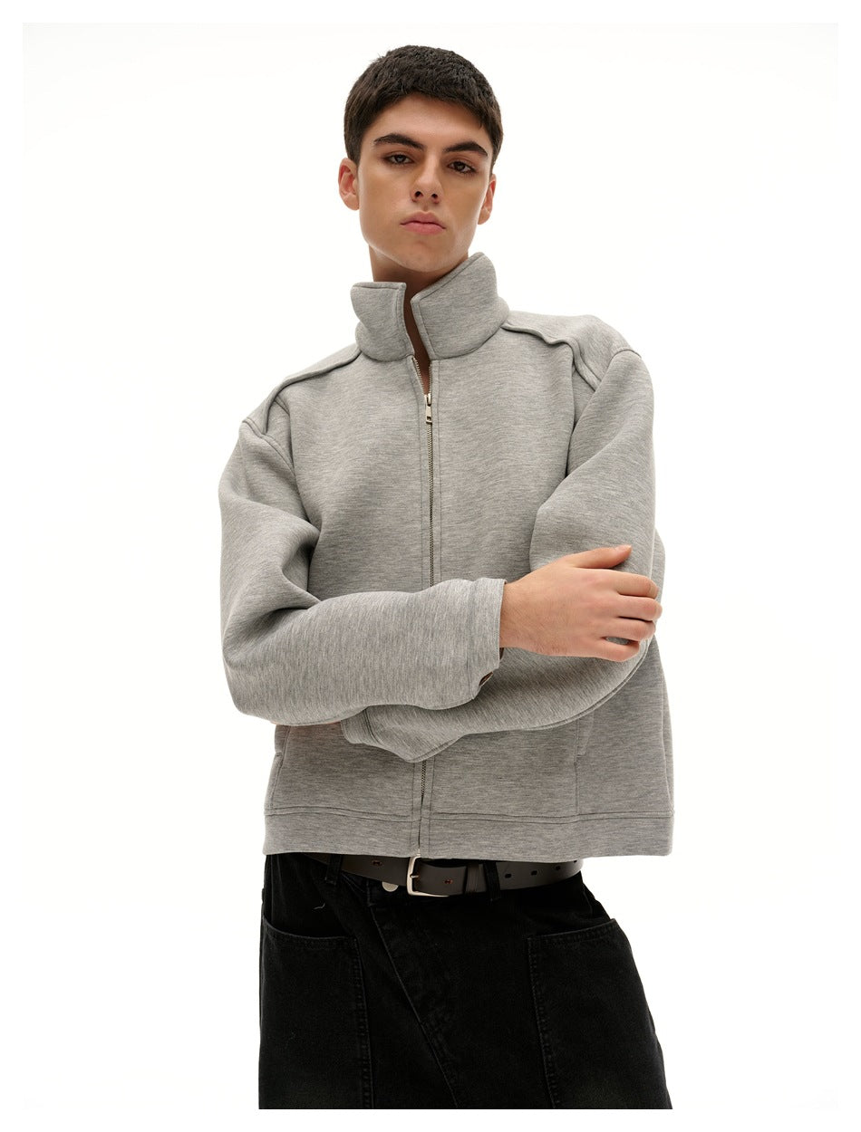 Model wearing the light gray jacket zipped to a tall collar, shown from the waist up.