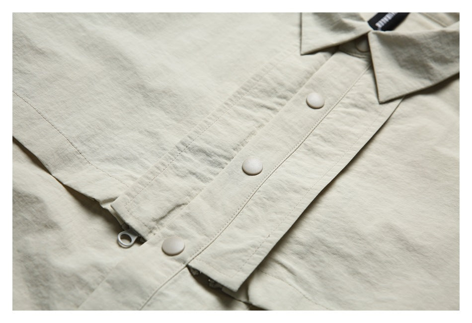 Close-up of the light beige shirt's snap-button front placket and collar.