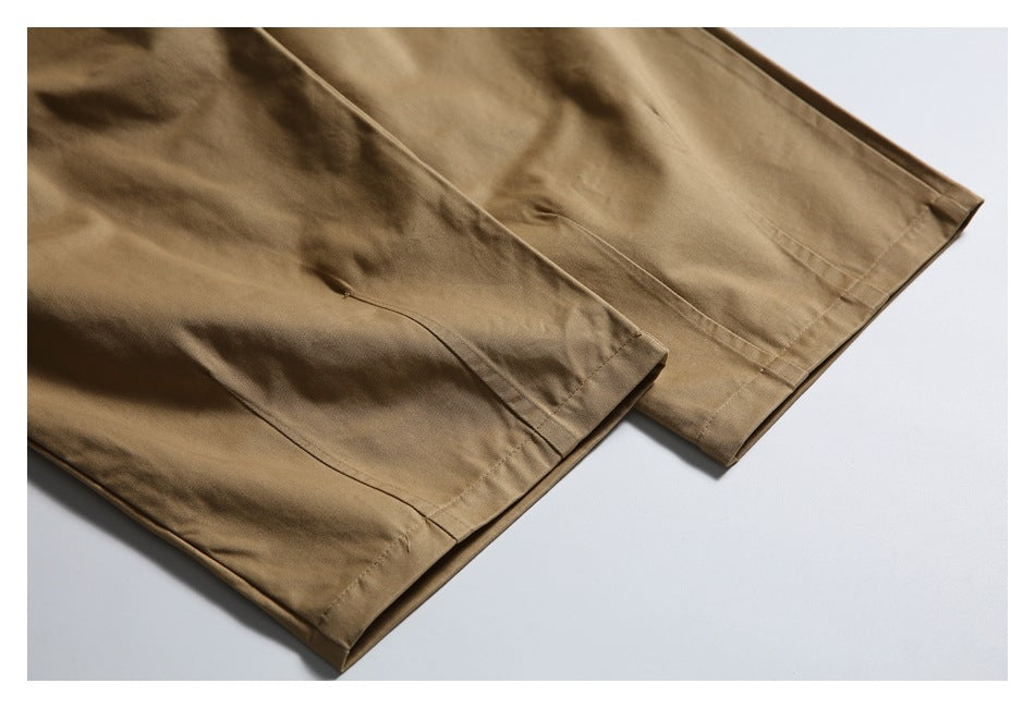Close-up of the stitched hems on tan trouser legs.