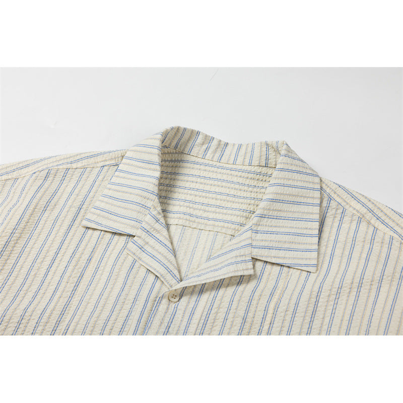 Close-up of a cream shirt collar and upper placket with fine blue and tan stripes.
