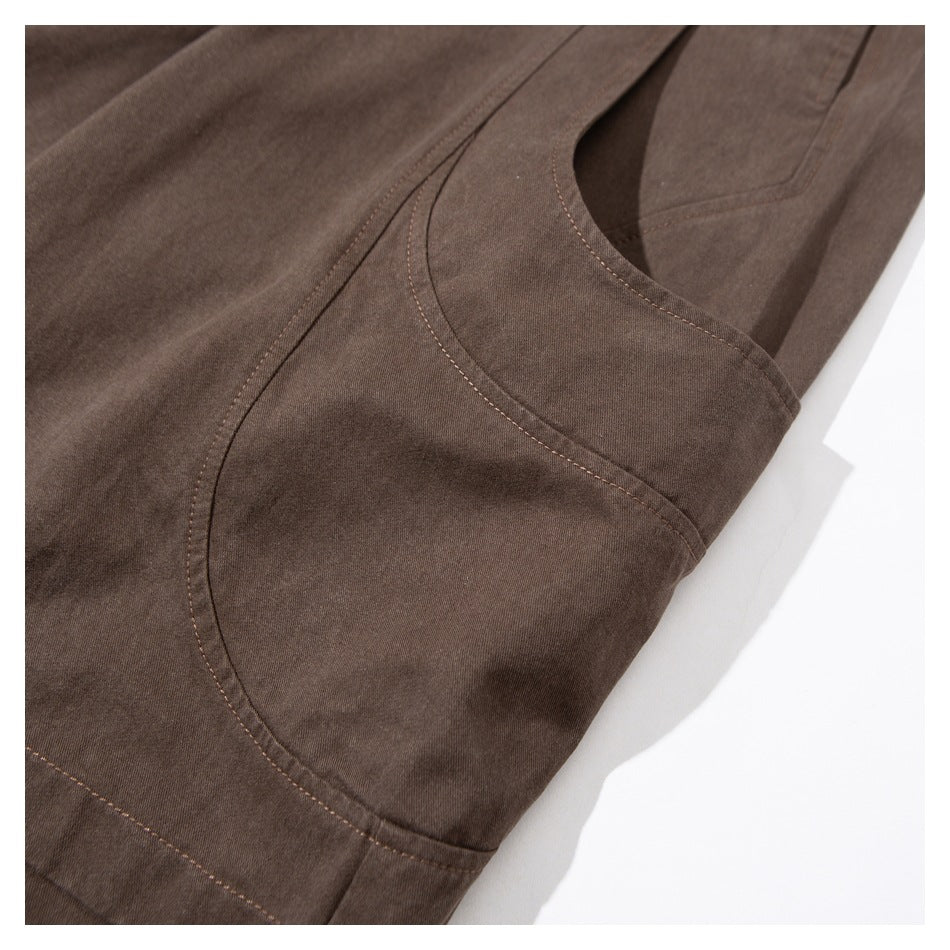 Close-up of brown pants showing curved stitched seams around the crotch and leg panel.