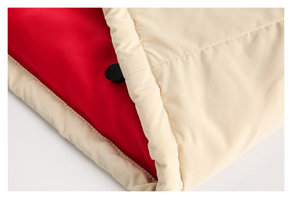 Close-up of a cream garment opened to show red lining and a black snap fastener.