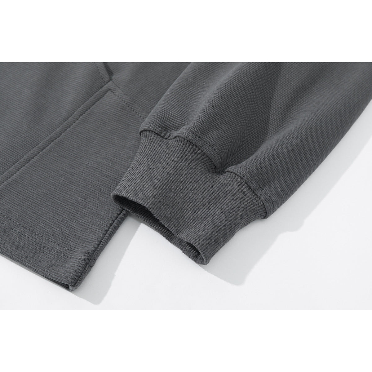 Close-up of a charcoal gray sweatshirt sleeve with a ribbed cuff and stitched hem.
