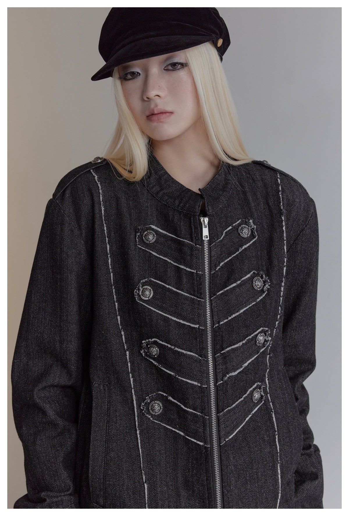 Close view of a model wearing a charcoal jacket with contrast seams, decorative buttons and a center zipper.