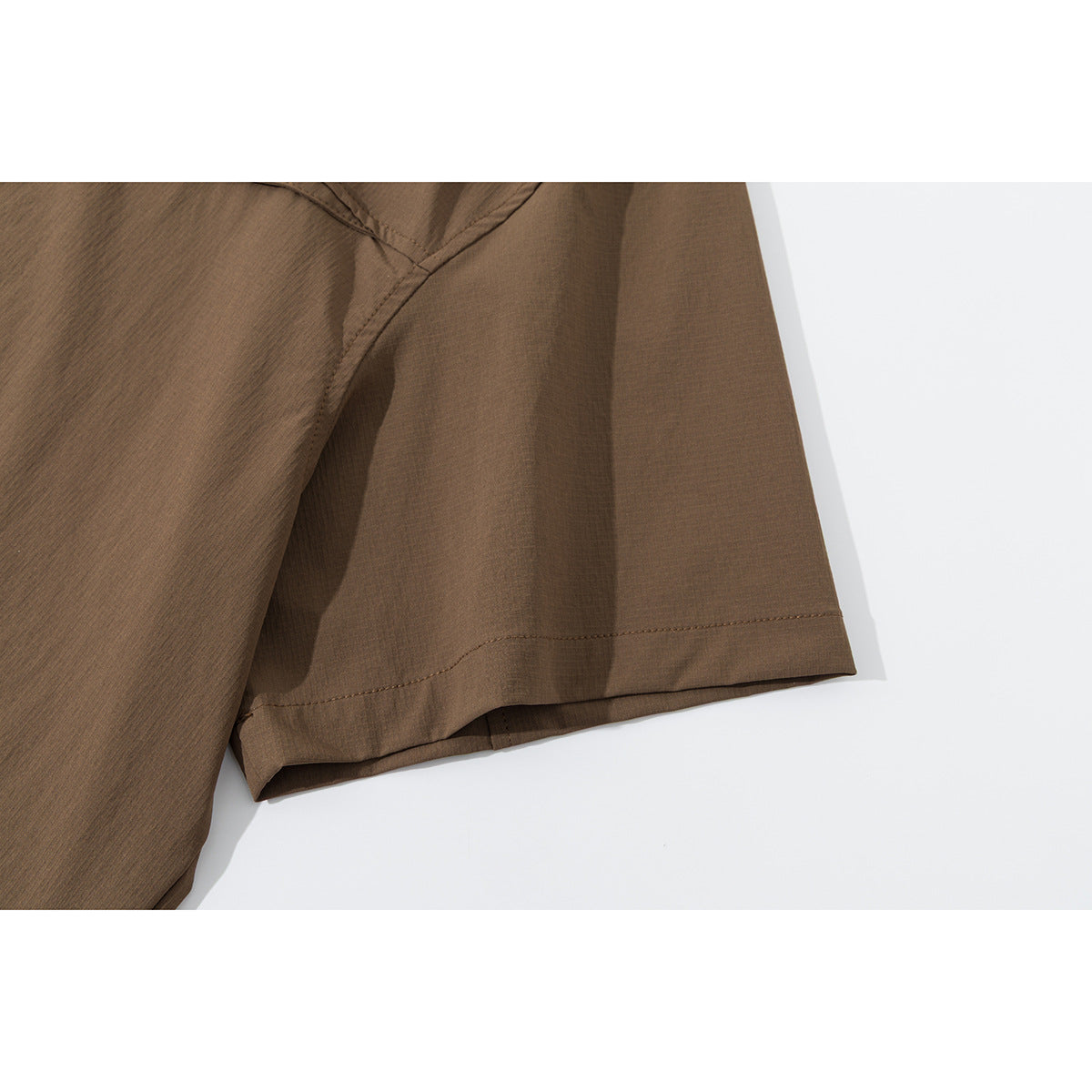 Close-up of the short sleeve and stitched hem of a brown shirt.