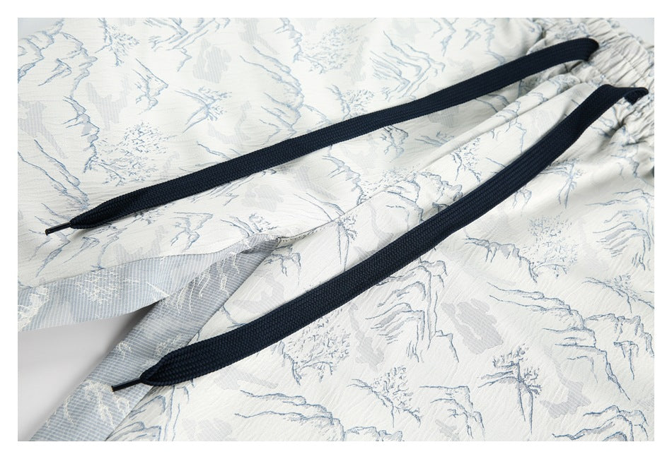 Close-up of pale blue and off-white printed shorts showing the gathered waistband and two dark drawstrings.