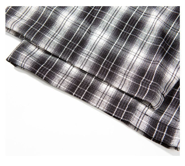 Close-up of the folded hem and stitching on a black-and-white plaid shirt.