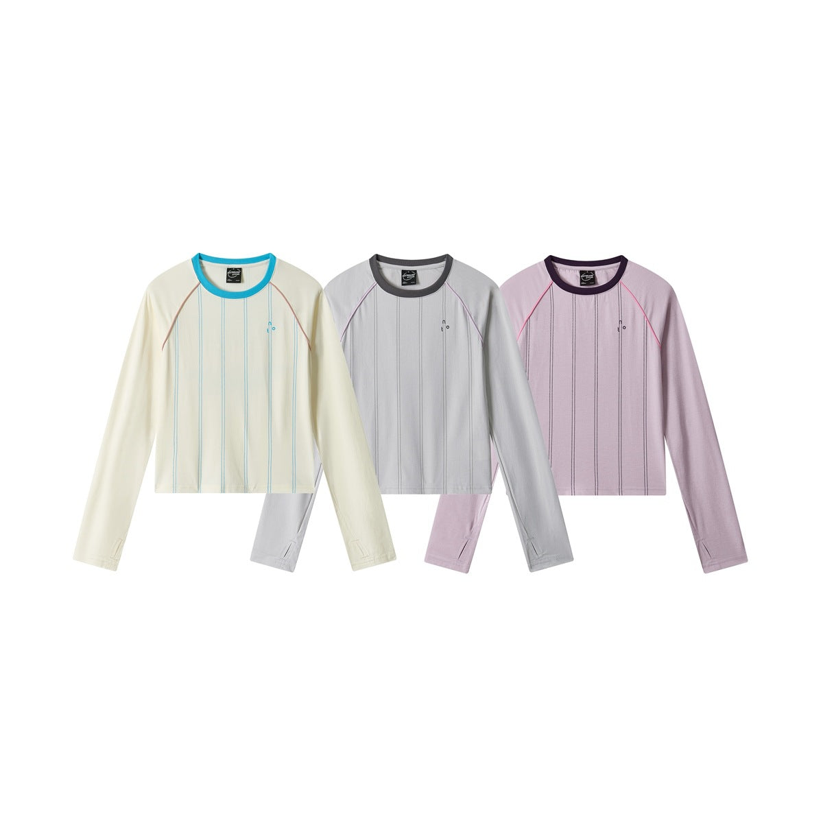 Three long-sleeve crewneck shirts in cream, light gray and pale lilac, each with vertical lines and contrast piping.