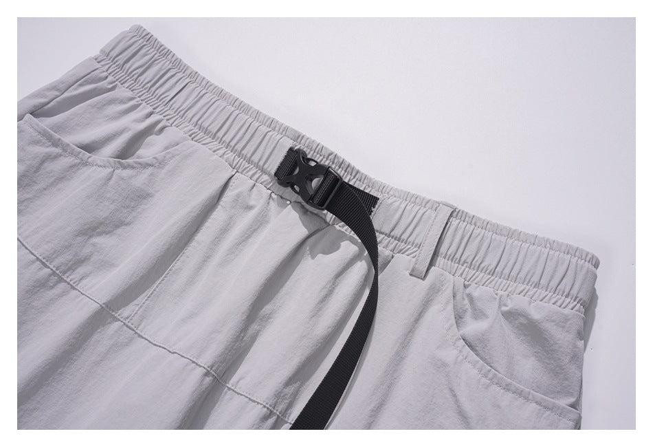 Close-up of the gray skirt's elastic waistband, black buckle strap, and curved side pockets.