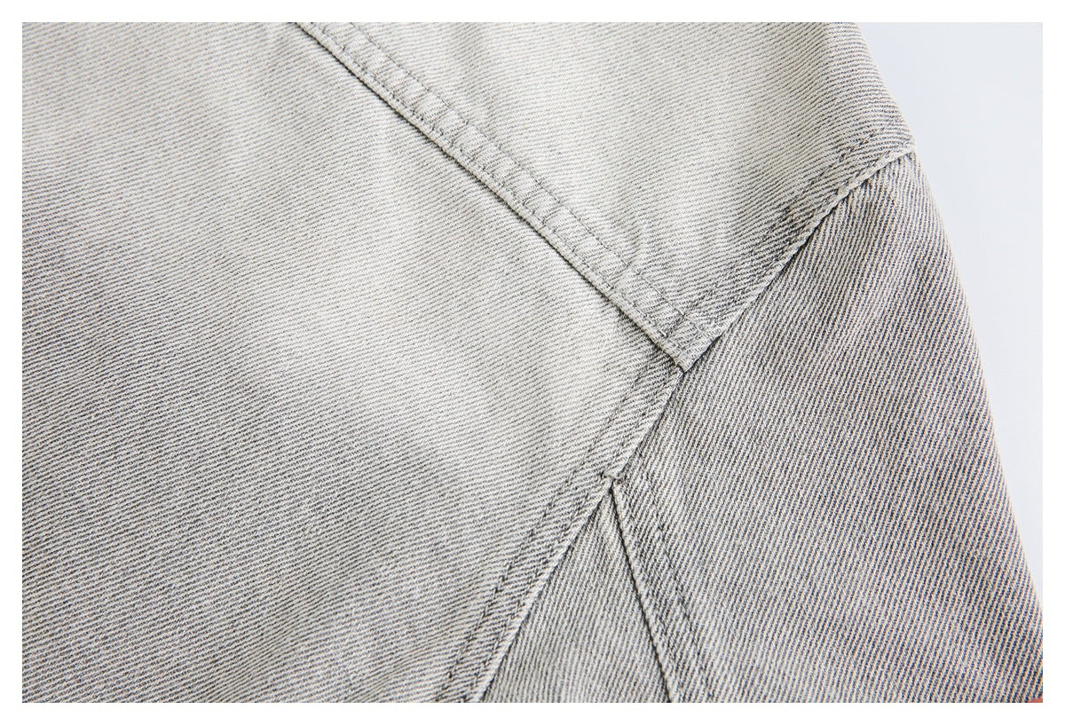 Close-up of pale gray washed denim with intersecting stitched seams.