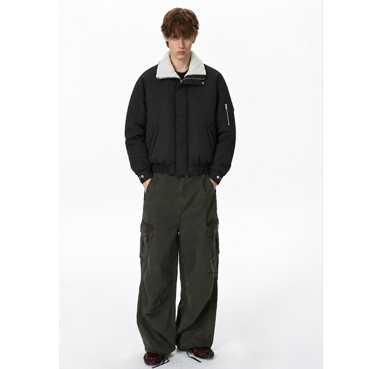 Model wearing a black jacket with a white fleece collar, zip sleeve pocket and olive cargo pants.
