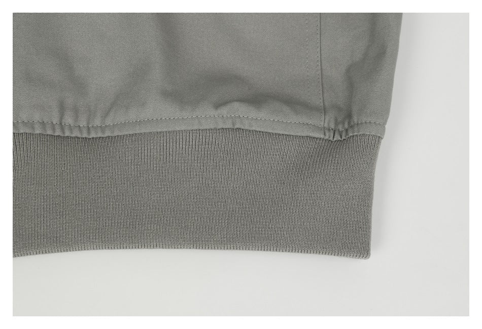 Close-up of the gray jacket's stitched lower edge and wide ribbed hem.