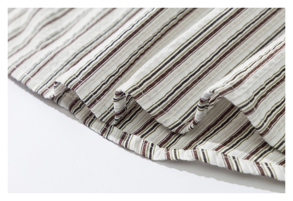 Close-up of the wavy stitched hem on a white garment with narrow brown, gray, and olive stripes.