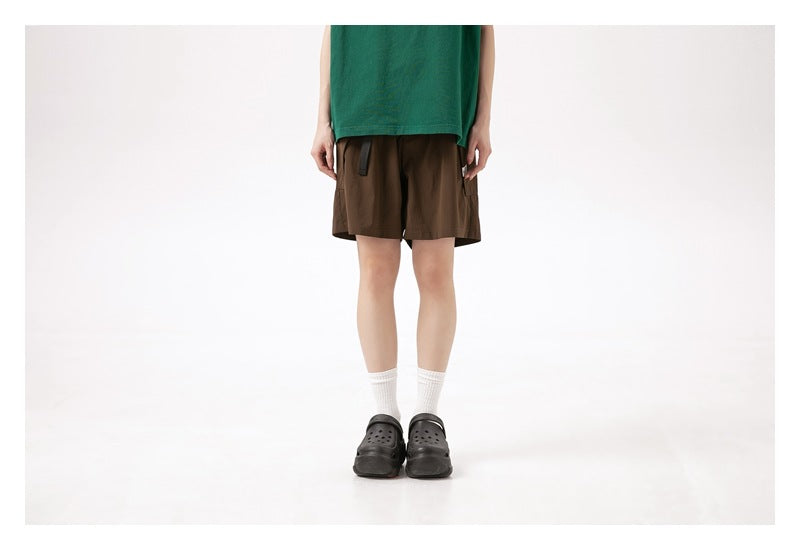 Front view of a model wearing brown knee-length shorts with a drawstring waist and side pocket.