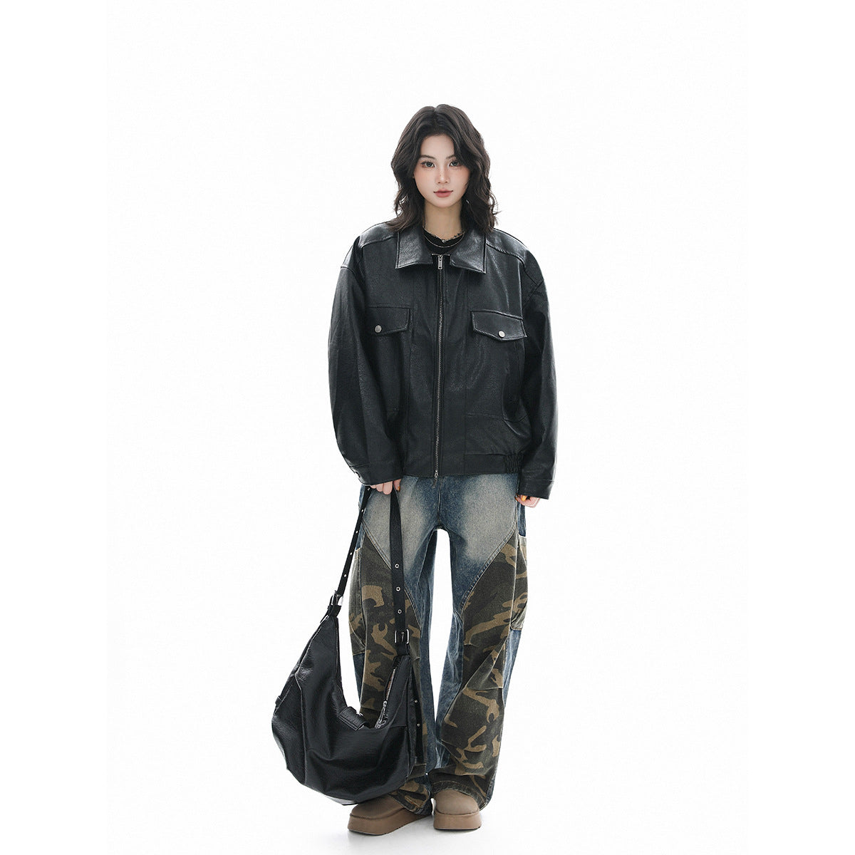 Model wearing an oversized black zip-front jacket with a wide collar and flap chest pockets, styled with patchwork jeans.