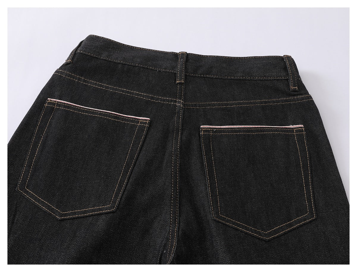 Back view of black denim jeans showing two patch pockets, belt loops and tan contrast stitching.