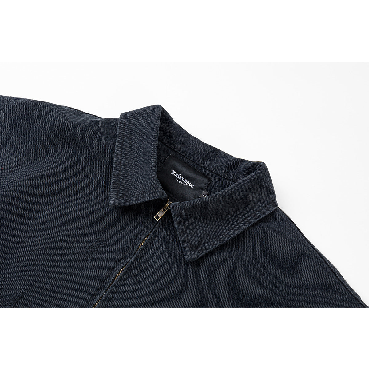 Close-up of a dark navy jacket showing its pointed collar, front zipper and inner neck label.