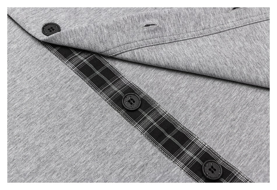 Close-up of a heather-gray garment with black buttons and a dark plaid-lined button placket.
