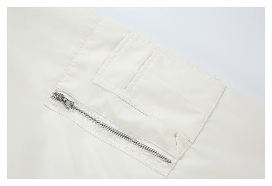 Close-up of a white sleeve pocket with a silver zipper and stitched flap.