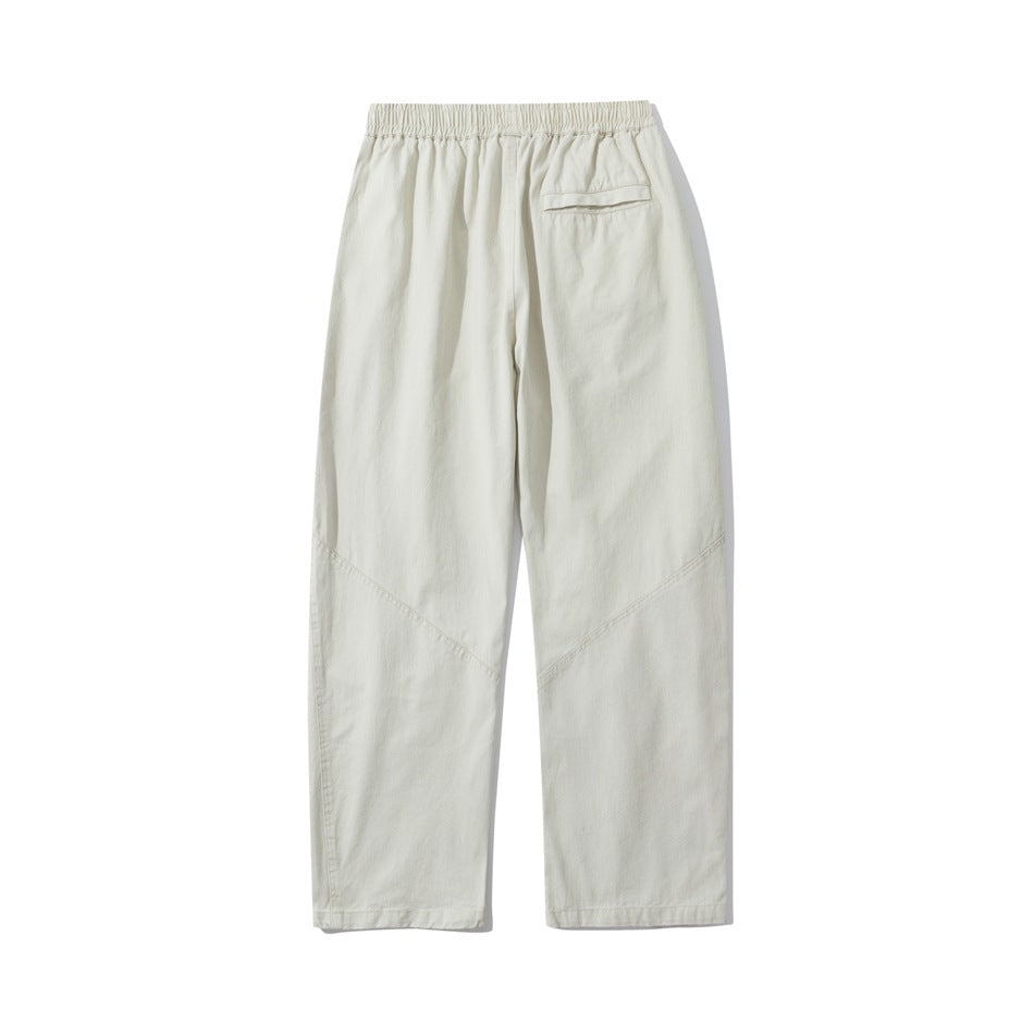 Back view of ivory loose straight-leg pants with an elastic waistband, a rear pocket, and angled leg seams.
