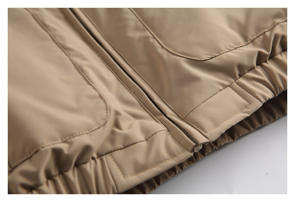 Close-up of the tan jacket's center zipper, lower pocket edge and gathered hem.