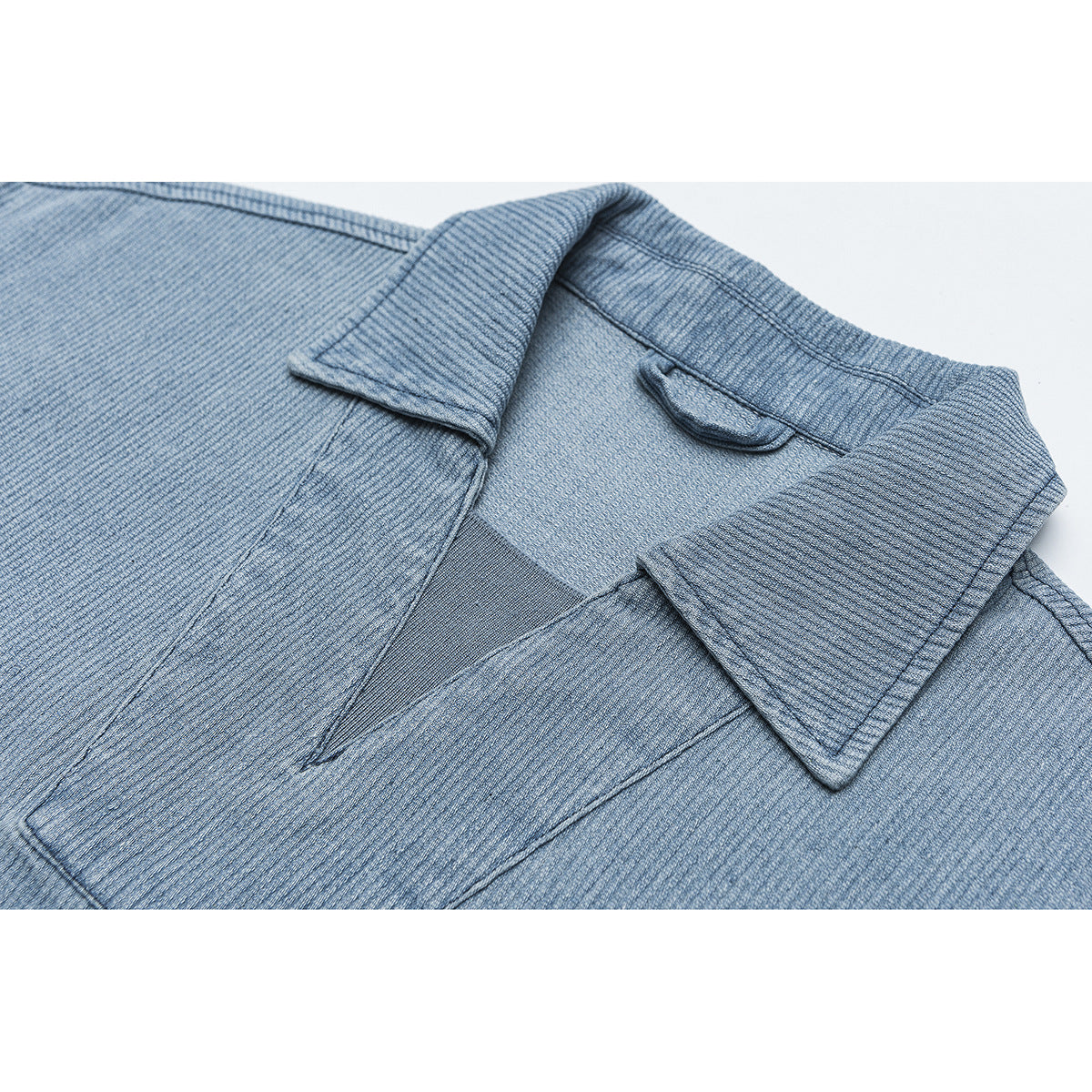 Close-up of a light blue textured jacket showing its pointed collar and front opening.
