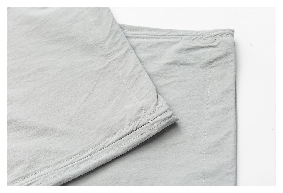 Close-up of light gray pant legs showing the stitched hem and seam construction.