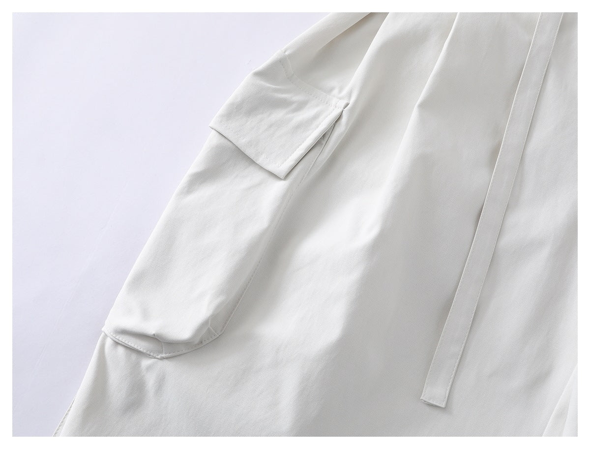 Close-up of white shorts showing a flap cargo pocket and a long hanging waist tie.