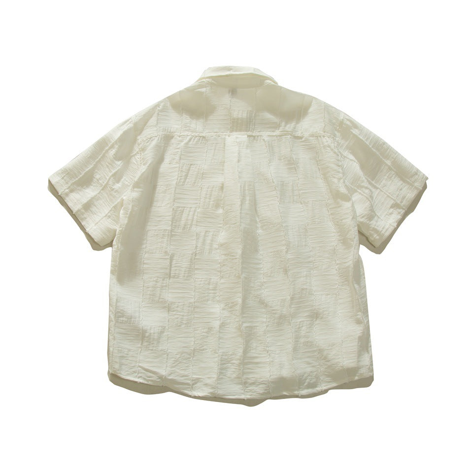 Back view of white short-sleeve shirt with crinkled checkered patchwork texture and raw-edge seams, flat lay