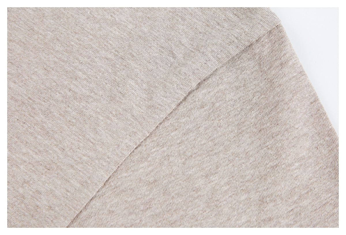Close-up of beige heather knit fabric with a diagonal shoulder or sleeve seam.