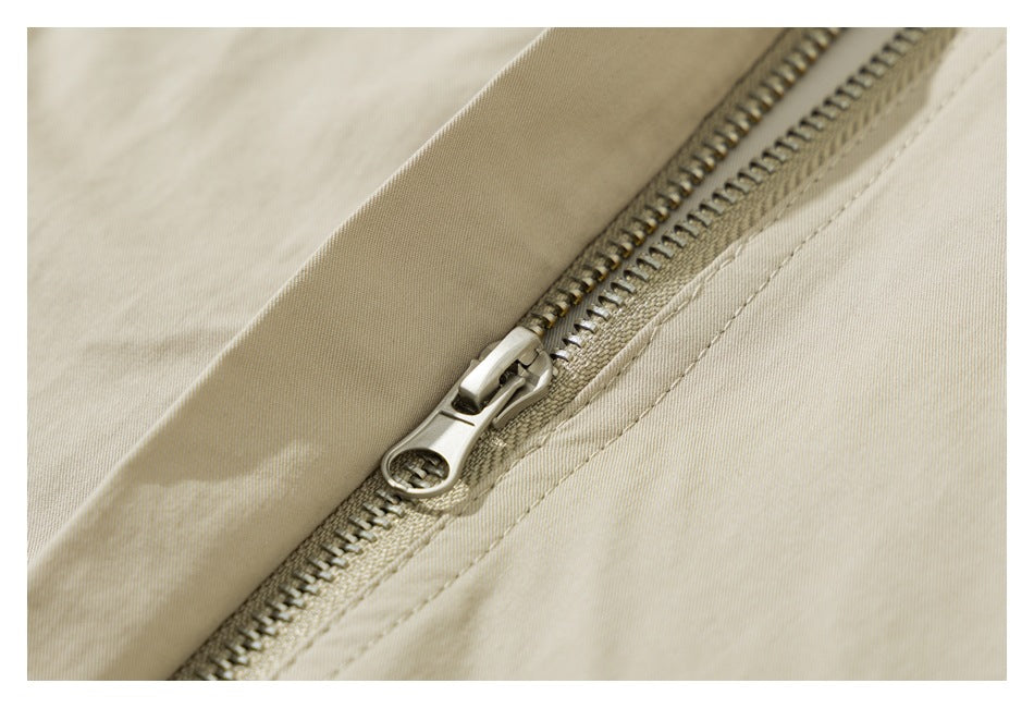 Close-up of a metal zipper and stitched seam on light beige fabric.