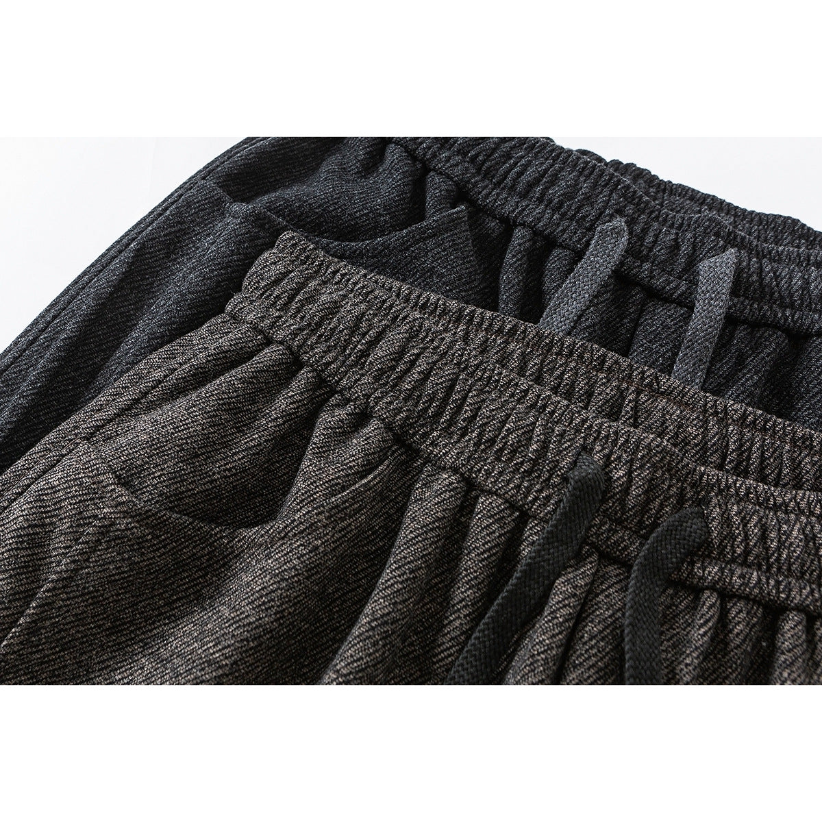 Close-up of charcoal and brown wide-leg trousers showing elastic waistbands and dark drawstrings.