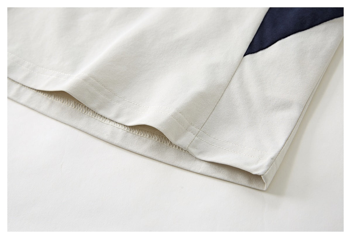 Close-up of the ivory shirt's stitched bottom hem, with a small navy color-block section.